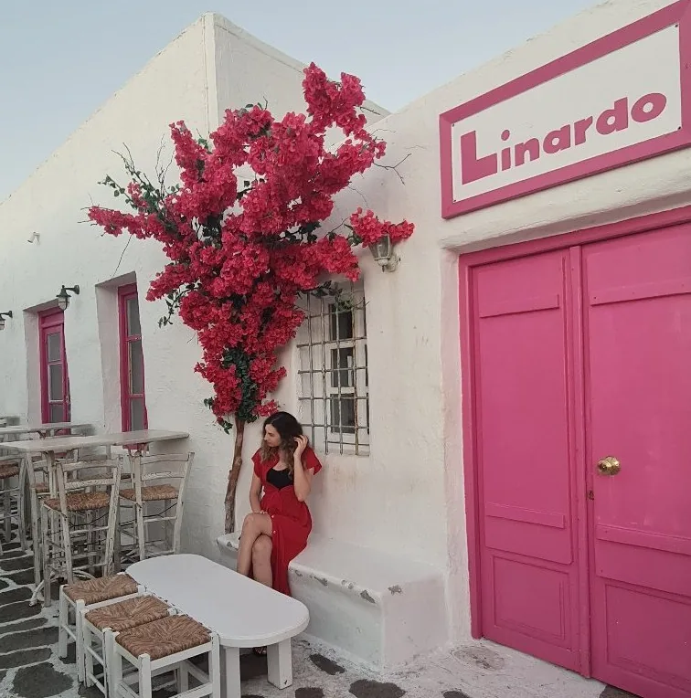 A bougainvillea in flower beside a bright pink doorway on a whitewashed Cycladic lane, Greece