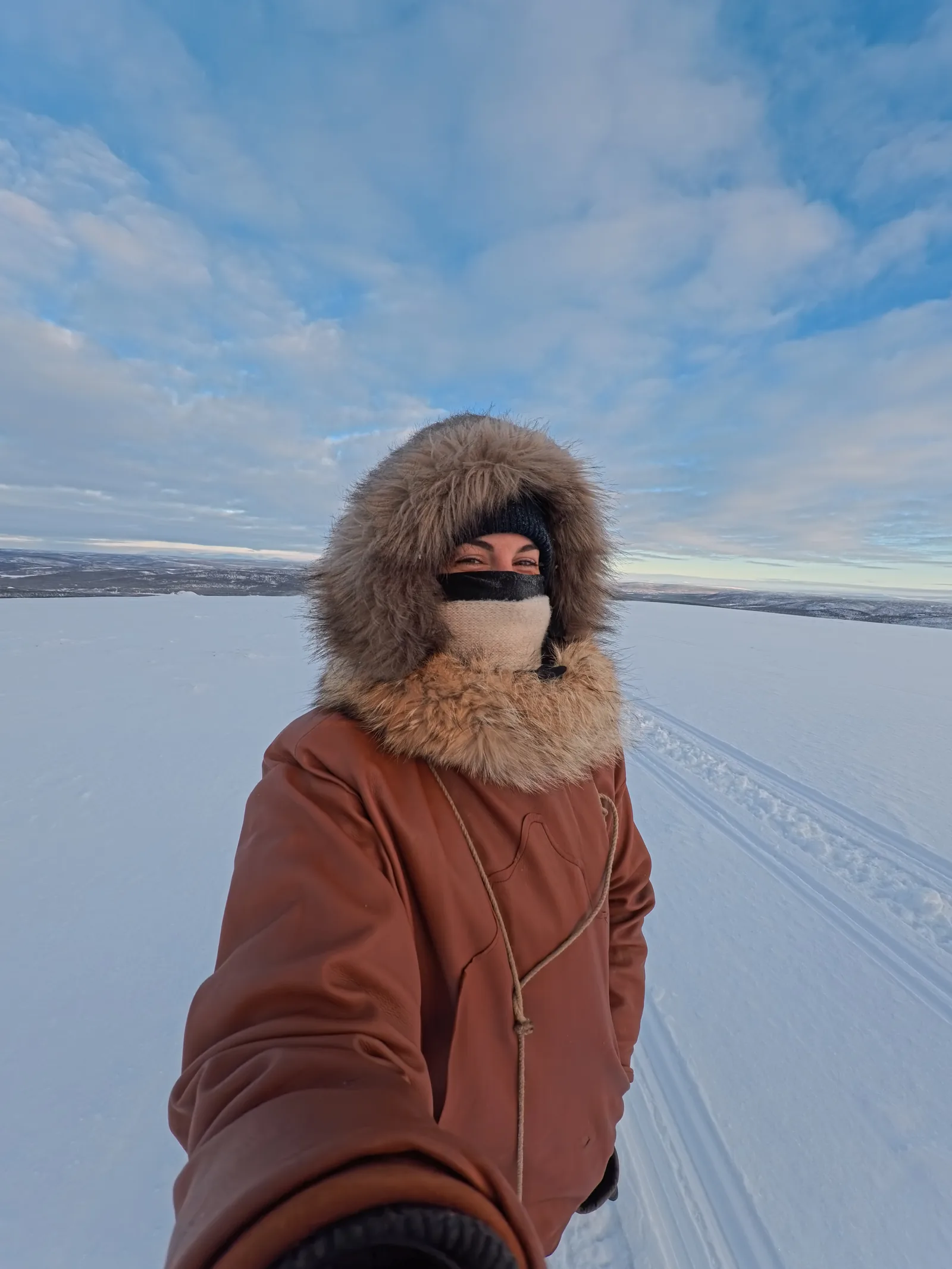 Cyrielle in a fur-hooded parka on a frozen plateau in Arctic Norway under a January sky