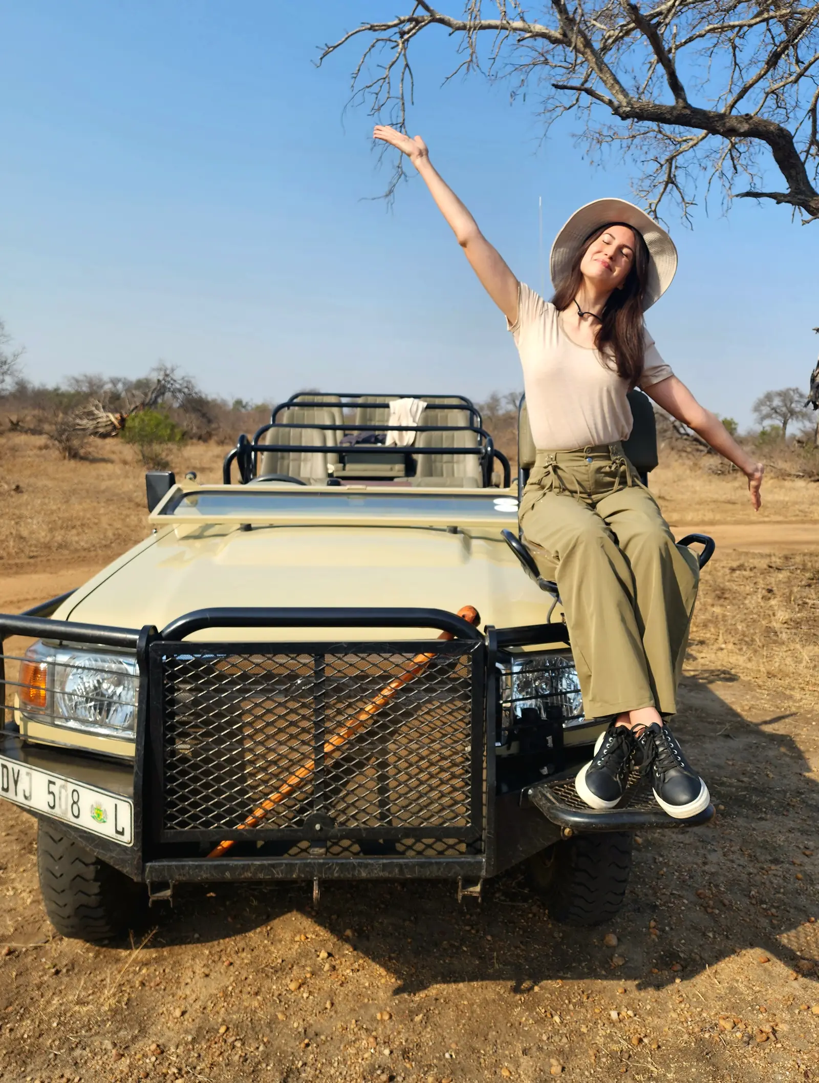 Traveller removing a fleece layer during a warming morning game drive.