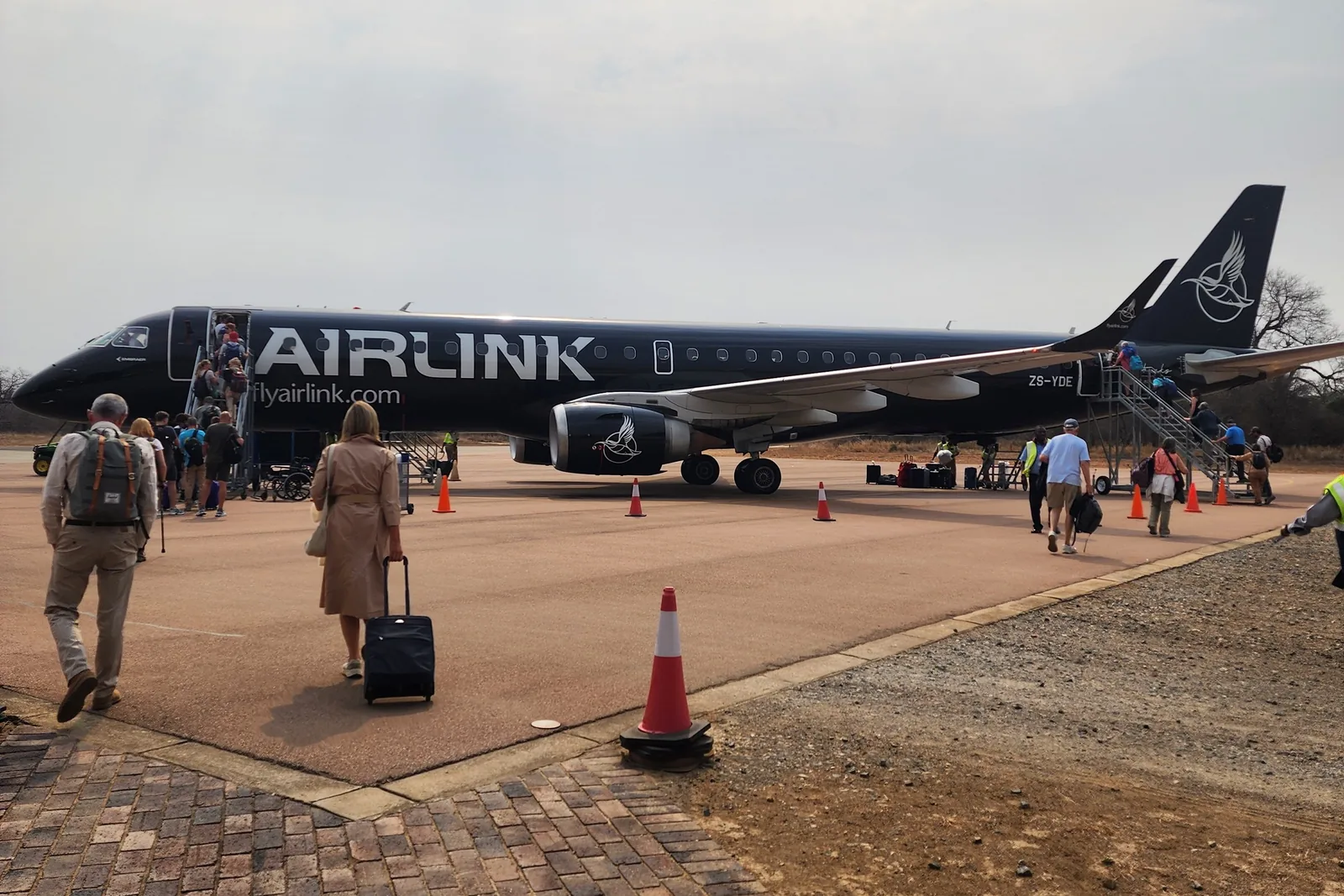 Passengers walking out to an Airlink aircraft on a bush airstrip in South Africa